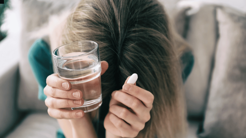 Žena v depresivním stavu s tabletou antidepresiva v ruce.