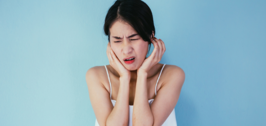 žena pociťující silnou bolest ucha.