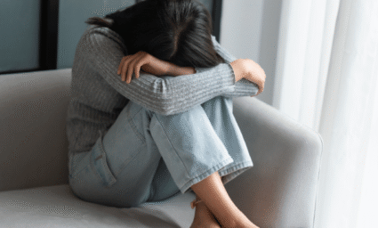 Žena sedící na gauči očividně v depresi.