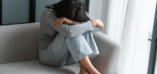 Žena sedící na gauči očividně v depresi.