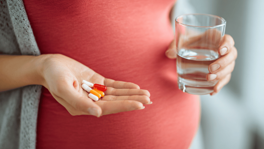 Těhotná žena doplňující důležité vitamíny k prevenci aftů.