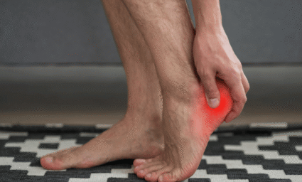 Muž držící se za bolavou patu.