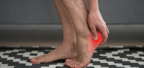 Muž držící se za bolavou patu.