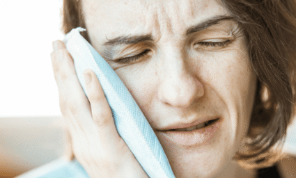 Žena držící si obklad na tváři.