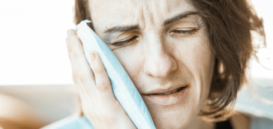 Žena držící si obklad na tváři.