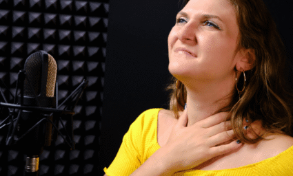 Zpěvačka držící se za krk.