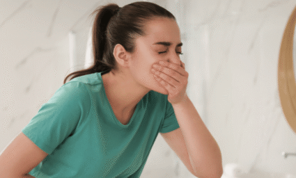 žena v koupelně, která se drží za ústa a břicho.