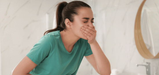 žena v koupelně, která se drží za ústa a břicho.