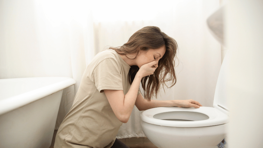 Těhotná žena skloněná nad záchodem.