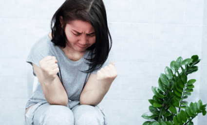 žena sedící na toaletě snažící se tlačit.