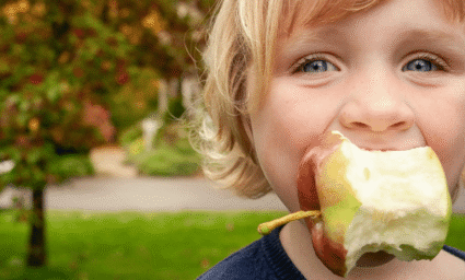 Dítě pojídající jablko.