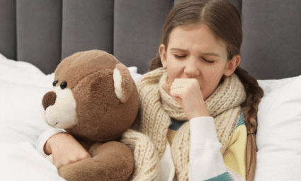 nemocná holčička v posteli s kašlem.