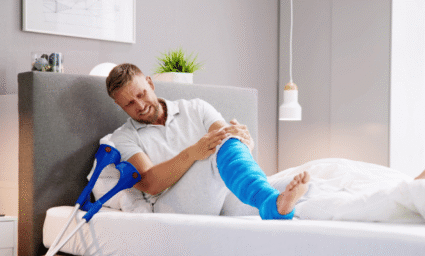 Člověk se zlomenou nohou v posteli.